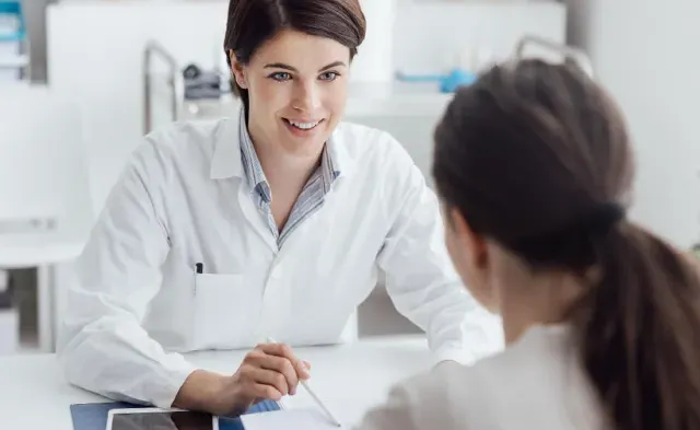 Adult-Gerontology Nurse Practitioner (AGNP) discussing treatment plan with patient 和 smiling